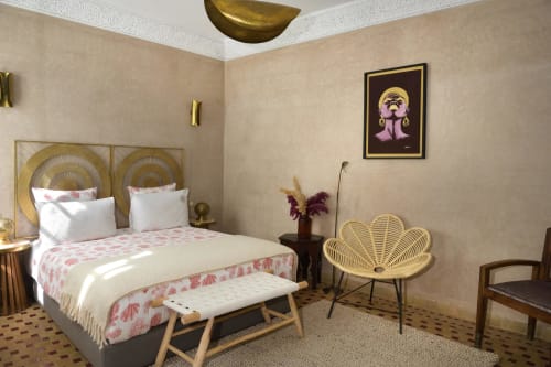 Sultana slaapkamer in Riad Palau Marrakech met gouden accenten, roze beddengoed en geweven stoel