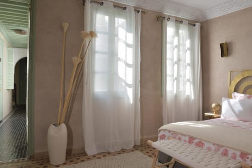Zonlit slaapkamer in Riad Palau Marrakech met witte gordijnen, crèmekleurige muren, decoratieve gedroogde bloemen en modern bed