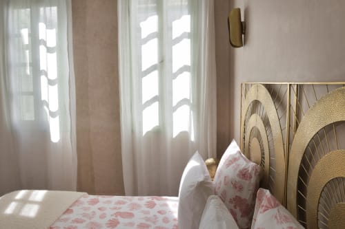 Lichte slaapkamer in Riad Palau Marrakech met verfraaide koperen hoofdeinde, roze bloemenbeddengoed en transparante gordijnen