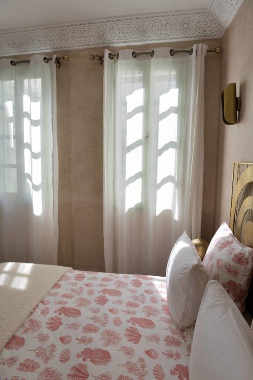 Lichte slaapkamer in Riad Palau Marrakech met sheer gordijnen, rood bedrukt beddengoed en gevlochten hoofdeinde