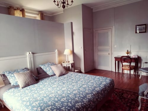 Suite du Maréchal élégante au Château de Bellevue avec literie fleurie bleue, cheminée blanche et vue sur le jardin