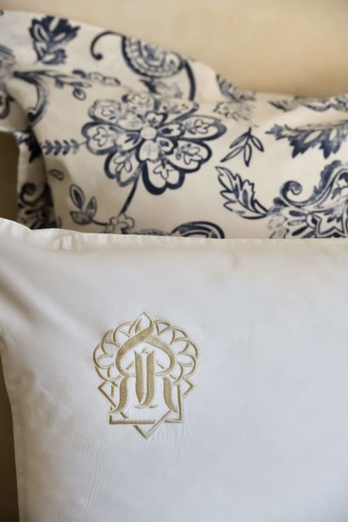 Luxe beddengoed in Riad Palau Marrakech met marineblauw bloemenpatroon kussens en wit gemonogrammd kussen met goudborduringen