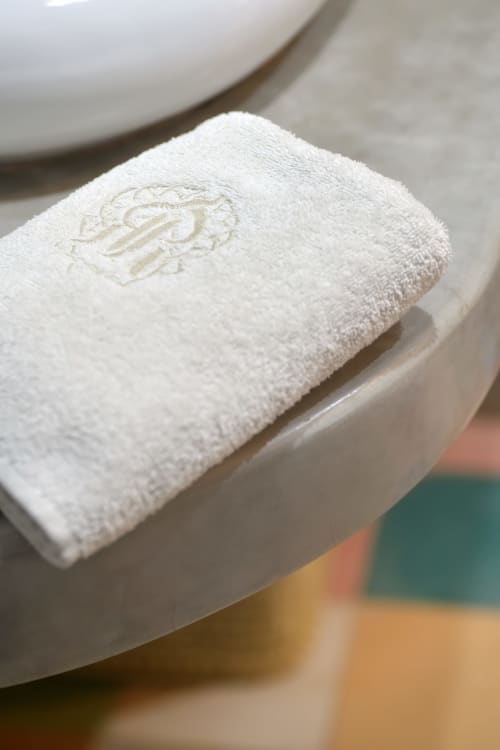 Opgerold wit handdoek met monogram op een wastafel in het Riad Palau Marrakech, een luxe riad in Marrakesh
