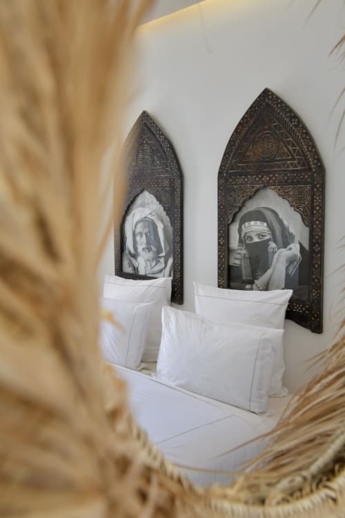 Slaapkamer van Riad Palau Marrakech met decoratieve Marokkaanse wandpanelen, witte kussens en sierlijke zwarte lijsten
