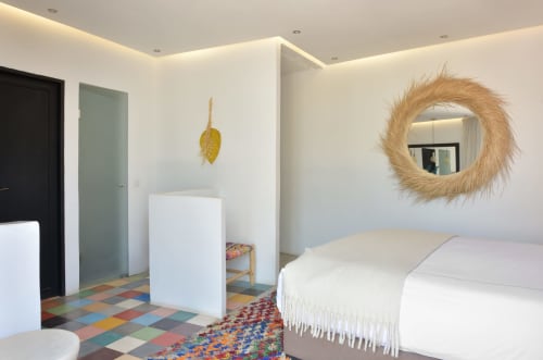 Moderne slaapkamer in Riad Palau Marrakech met wit bed, geweven spiegel, kleurig tegelvloer en eigentijds meubilair