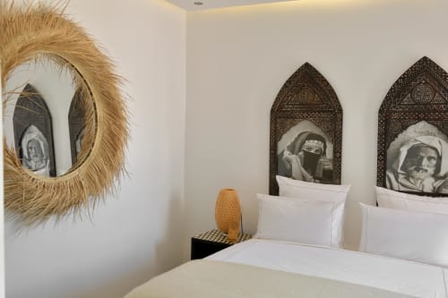 Slaapkamer in Marrakech riad met ingeweven gesneden houten panelen, geweven stroien spiegel en traditionele zwart-witte portetten