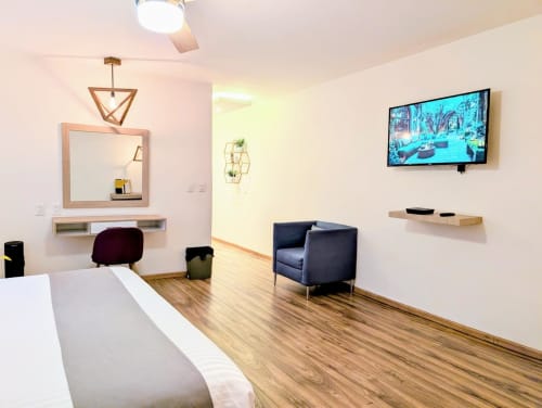 Estudio moderno en Casa Donceles, México con cama king, sillón azul marino, TV de pared y escritorio de madera