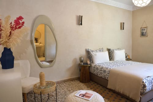 Stijlvolle slaapkamer van Riad Palau in Marrakesh met hedendaags decor, gemusterd beddengoed, ovale spiegel en geweven accenten