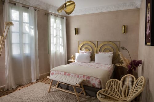 Luxe slaapkamer in Riad Palau Marrakech met gouden accenten, koperen hoofdeinde, witte kussens en pauwenstoel