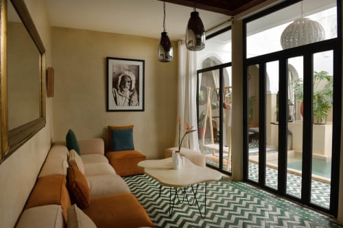 Modern zitgedeelte met oranje en beige zitmeubels, zwart omlijste deuren naar de binnenplaats van Riad Palau Marrakech