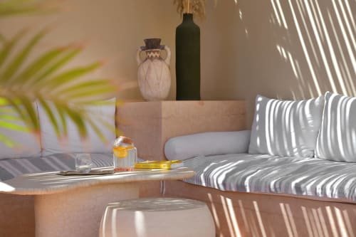 Zonnige slaapkamer van Riad Palau Marrakech met gestreepte zitplaatsen, decoratieve vazen en palmen