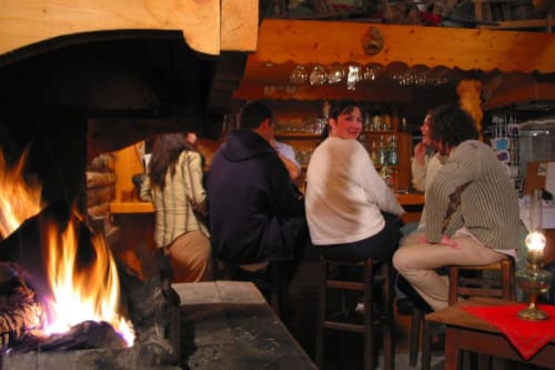 Guests gather around a fireplace at Auberge Nemoz, a French B&B, enjoying conversation by the warm fire in a rustic lodge