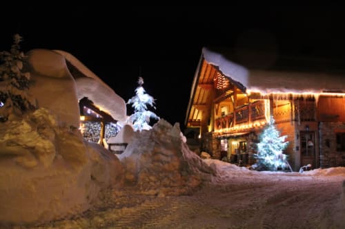 Auberge Nemoz in Le Haut-Bréda at night with illuminated buildings and decorated trees in snow