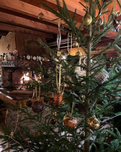 Rustic Christmas decor at Auberge Nemoz with decorated evergreen branches, ornaments, and fireplace