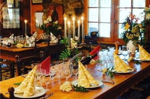 Elegant dining table at Auberge Nemoz with yellow napkins, red place cards, wine glasses, and candles