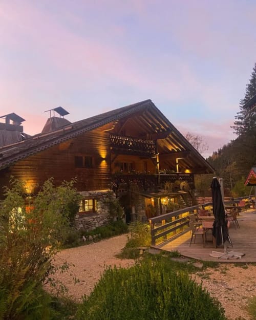Auberge Nemoz lodge at twilight, Le Haut-Bréda, with illuminated wooden architecture and forest backdrop