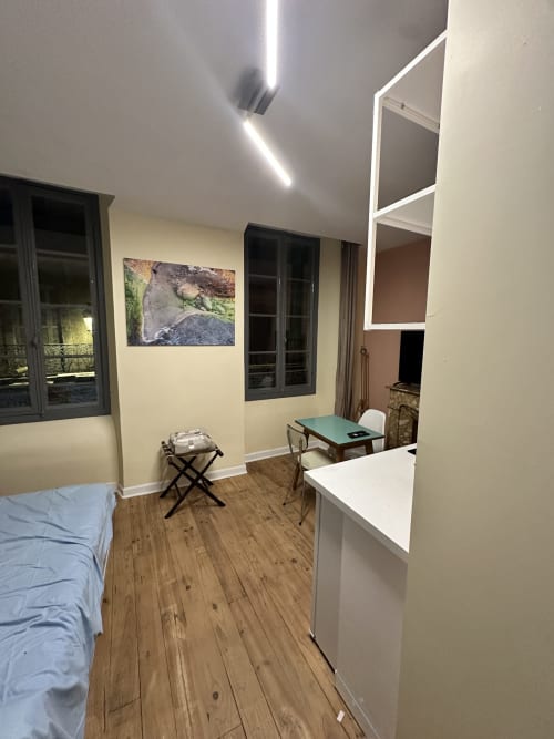 Modernes Apartment in Lourdes mit Holzboden, Bett, Arbeitstisch, Kochnische und gerahmte Naturkunst an cremefarbenen Wänden