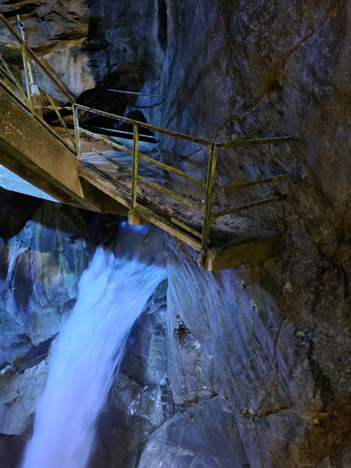 Cascading waterfall flowing through rocky gorge with yellow metal railings near Villa Vista Lago di Como, Bellano