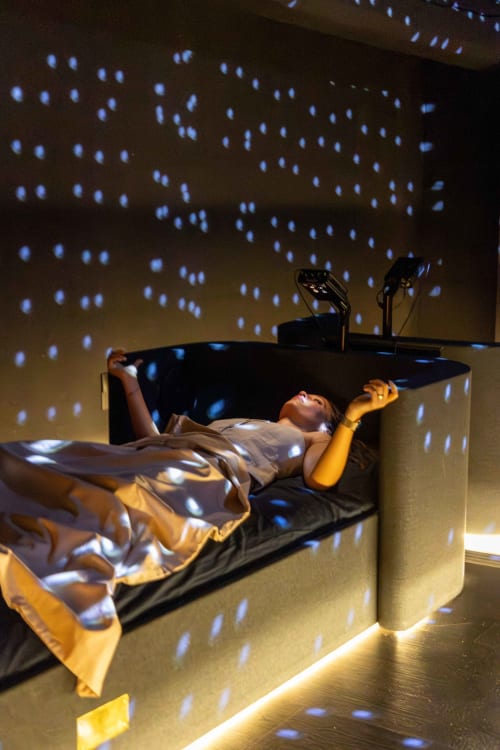 Guest relaxing on curved bed with blue light projection at Maison de Sophie boutique hotel in Rencurel