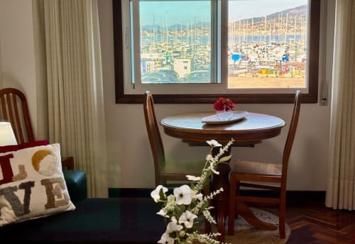 Elegante comedor en apartamento de Baiona con vistas al mar, mesa de madera y vista a la marina desde las ventanas