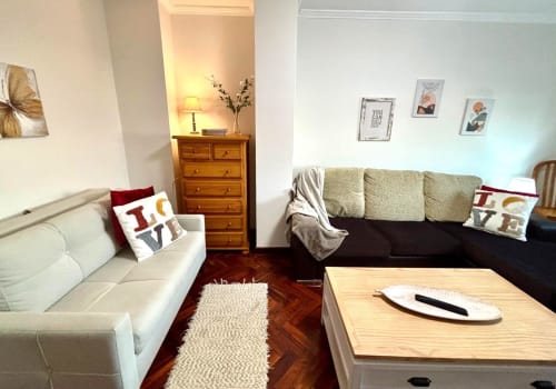 Acogedora sala de estar del apartamento Exeira en Baiona con sofá crema, butaca oscura, arcón de madera y decoración marina