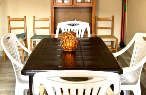 Comedor del apartamento en Baiona con mesa negra, sillas blancas y adorno decorativo ámbar