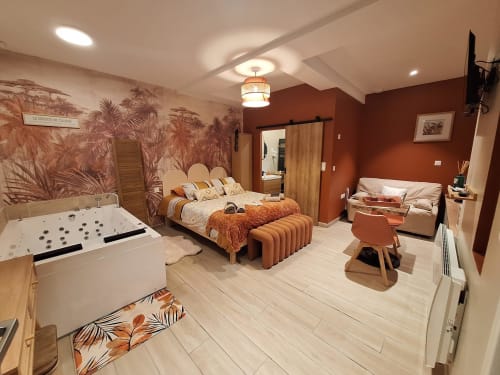 Chambre luxueuse de La Cour d'Hortense aux murs orangés, baignoire spa, lit king-size et vue sur le jardin