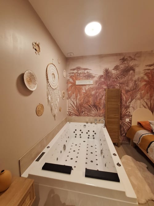 Baignoire de luxe avec jets de massage à La Cour d'Hortense, salle de bain décorée d'art mural tissé et de peinture tropicale