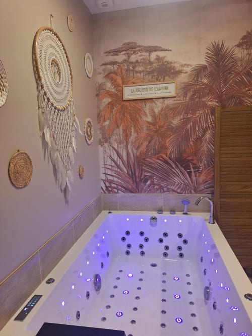 Baignoire de luxe avec éclairage ambiant violet et jets de massage à La Cour d'Hortense, décorée avec mobilier africain
