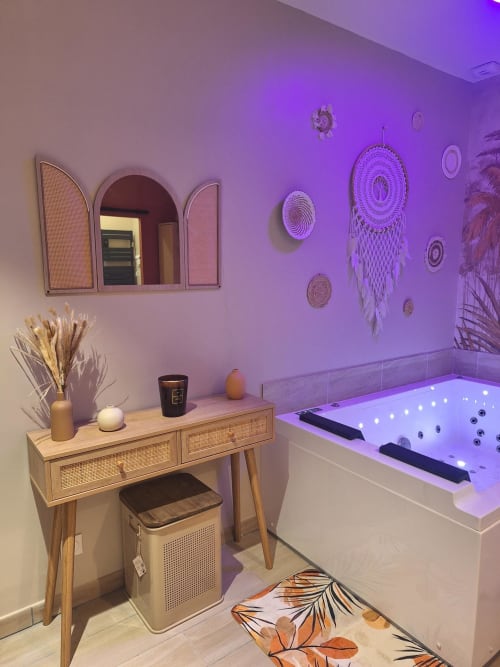 Salle de bains spa moderne à La Cour d'Hortense avec éclairage ambiant violet, bain à remous illuminé, meuble-lavabo en bois et éléments décoratifs