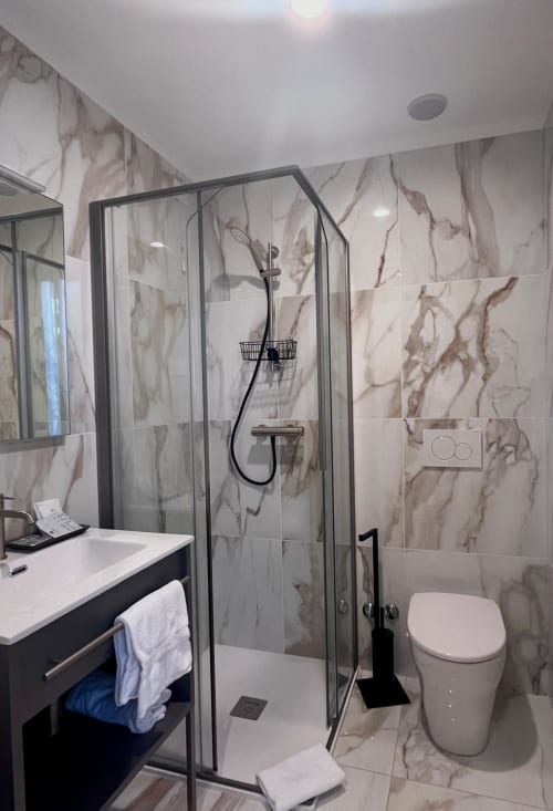 Modern bathroom at Casanova Hideaway Venice with marble tiling, glass shower enclosure, and white sink vanity