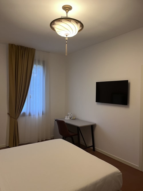 Camera moderna del Casanova Hideaway Venice con letto, scrivania, TV a parete e lampada a sospensione