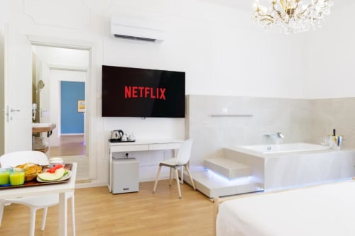 Modern studio room at Bluemoon Sardinia in Cagliari with Netflix-enabled TV, workspace, kitchenette, and bathtub with ambient