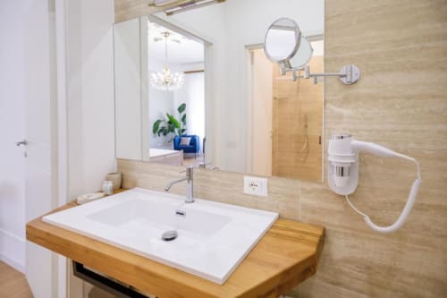 Modern bathroom at Bluemoon Sardinia Cagliari with wooden vanity, white sink, and illuminated mirror