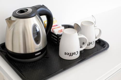 Welcome coffee and tea service setup at Bluemoon Sardinia hotel in Cagliari with kettle and mugs on black tray