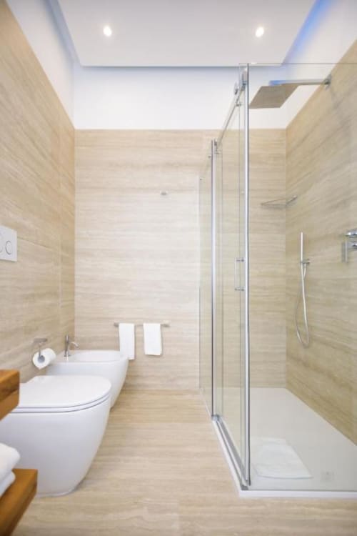 Modern bathroom at Bluemoon Sardinia with walk-in shower, white toilet, and light wood tiles in Cagliari