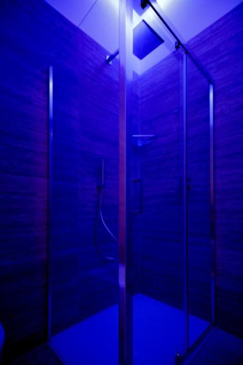 Modern shower enclosure with blue neon lighting at Bluemoon Sardinia boutique hotel in Cagliari