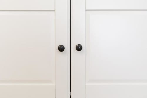 White wardrobe doors with black knobs in Bluemoon Sardinia hotel room, Cagliari