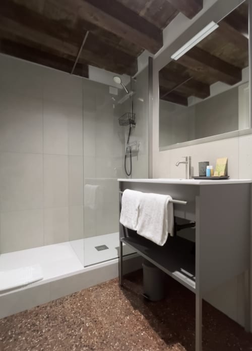 Bagno moderno al Casanova Hideaway Venezia con doccia in vetro, lavabo bianco, portasciugamani e pavimento in terrazzo