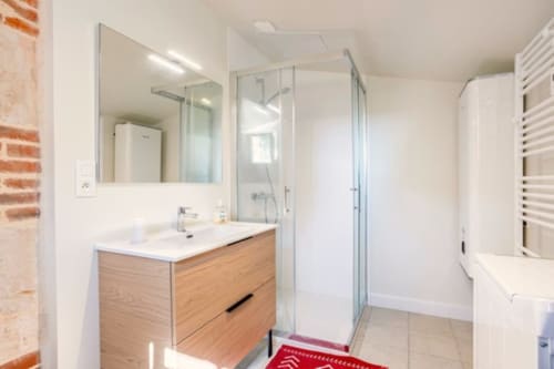 Salle de bain moderne avec meuble-lavabo en bois, douche à l'italienne et porte-serviettes chauffant au gîte Château de Bellevue, Sainte-Cécile