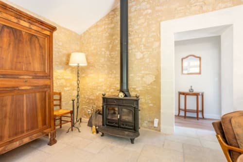 Salon rustique du Château de Bellevue avec poêle en bois noir, mobilier en bois et cheminée en pierre
