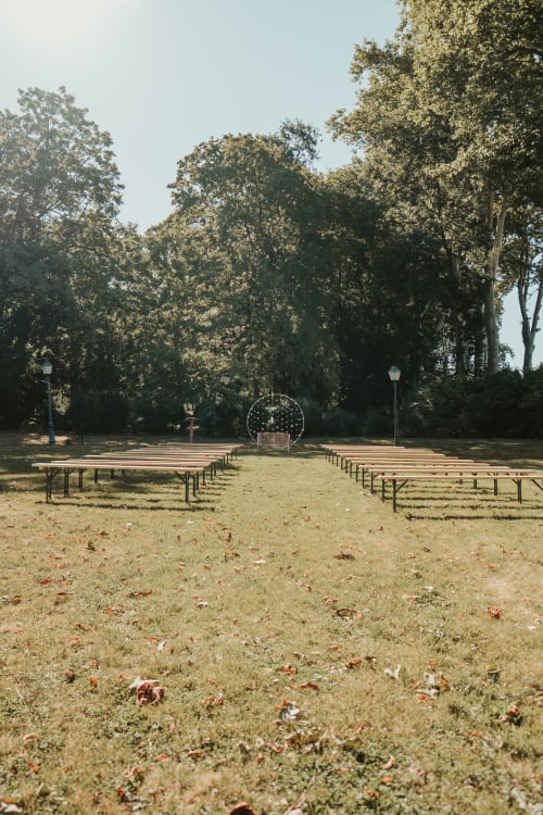 Espace de détente extérieur à l'auberge La Maison Verneuil à Paray-le-Monial avec bancs en bois sous de grands arbres