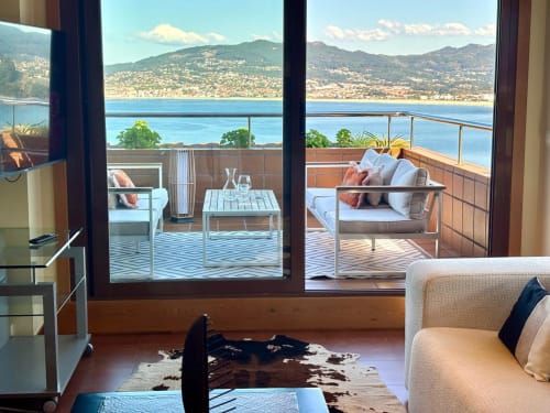 Lujoso apartamento dúplex con vistas al mar en Baiona, España. Sala de estar moderna con grandes ventanales con vista al Mar