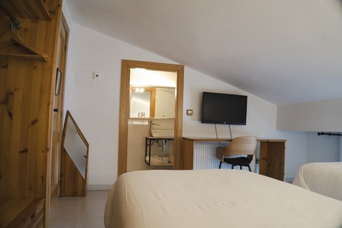 Habitación moderna en Hostal El Ciervo, Villaciervos con camas gemelas, TV plana, muebles de madera y baño privado