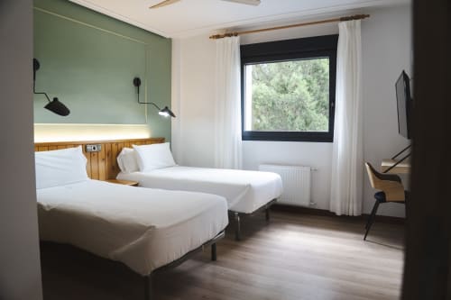 Habitación doble en Hostal El Ciervo con camas blancas, pared verde y ventana con vistas a Villaciervos