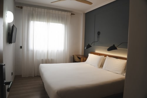 Habitación moderna en Hostal El Ciervo de Villaciervos con cama queen, TV de pared y luz natural