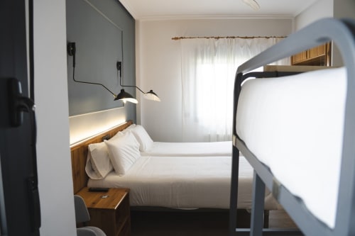 Dormitorio moderno en Hostal El Ciervo de Villaciervos con camas gemelas, iluminación colgante y decoración contemporánea