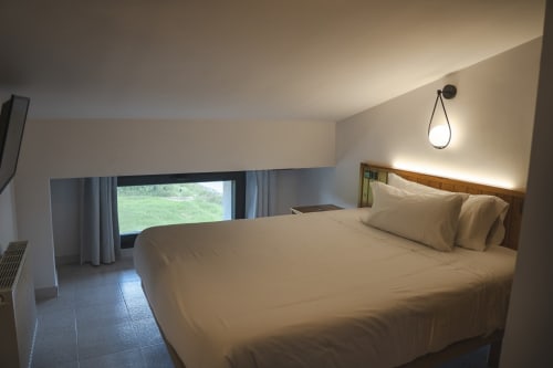 Habitación luminosa en Hostal El Ciervo con cama queen, vistas a la montaña, lámpara colgante y mobiliario moderno