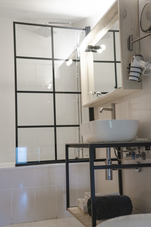 Baño moderno en Hostal El Ciervo con ducha tipo walk-in, lavabo tipo vessel y diseño de marco metálico negro