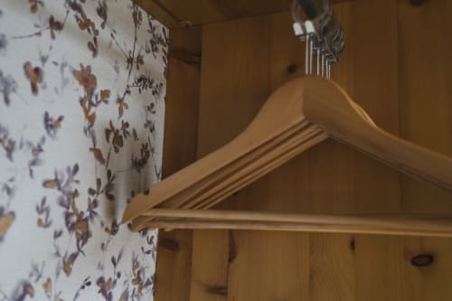 Perchero de madera en habitación de hostal Hostal El Ciervo, Villaciervos, con papel tapiz floral y revestimiento de madera